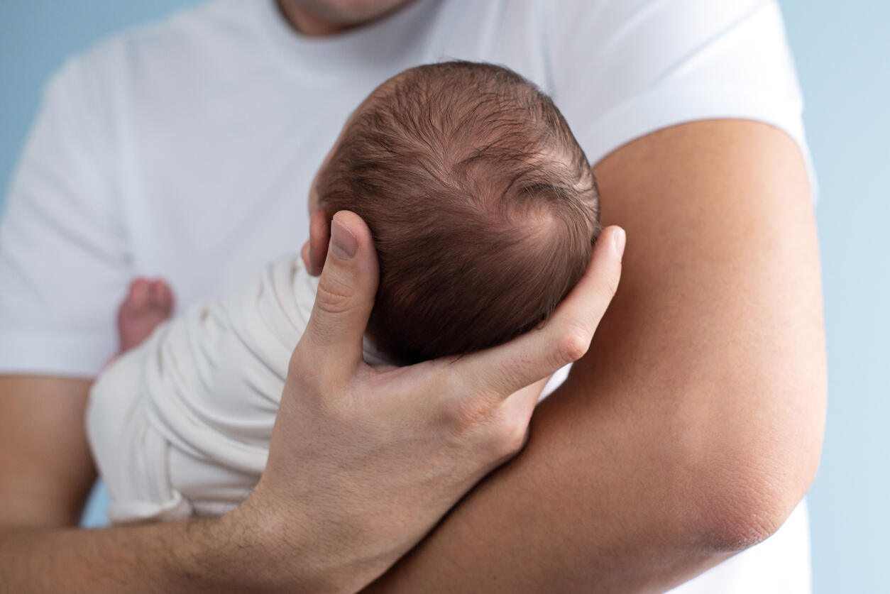 Close-up of a parent cradling an infant, representing the sensitive nature of paternity cases for families.