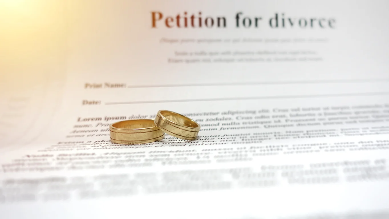 Divorce petition document with wedding rings, symbolizing the concept of 'irreconcilable differences' in California divorces.