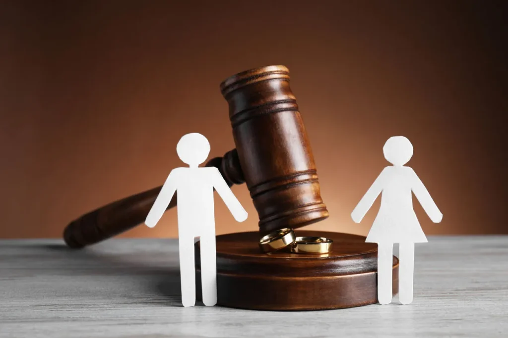 Paper figures representing a man and woman with wedding rings, symbolizing divorce in a courtroom setting.