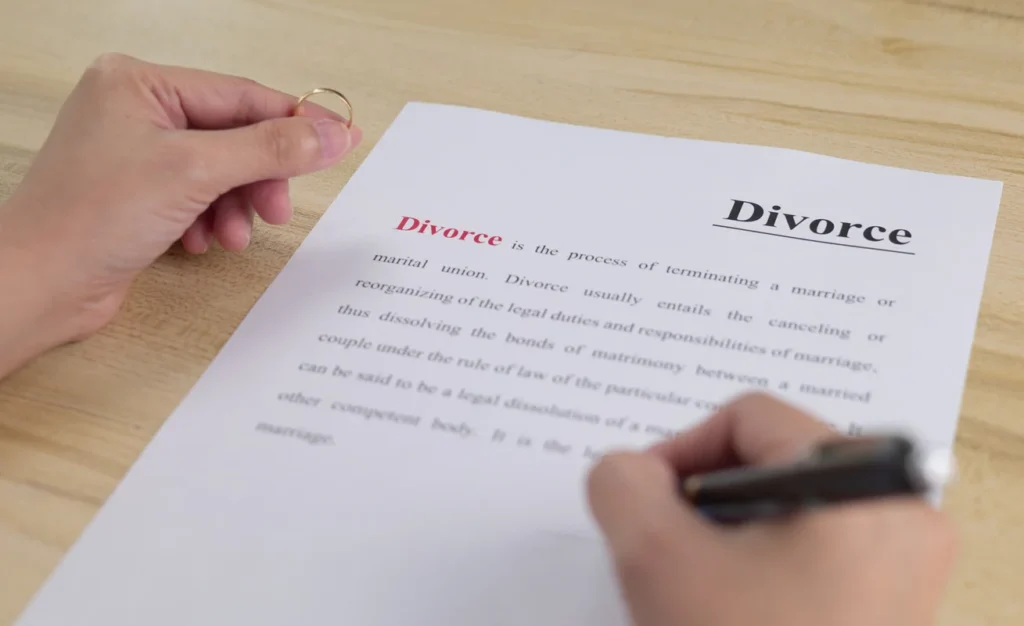 Hand holding a wedding ring over a divorce document, highlighting temporary orders in contested divorces.