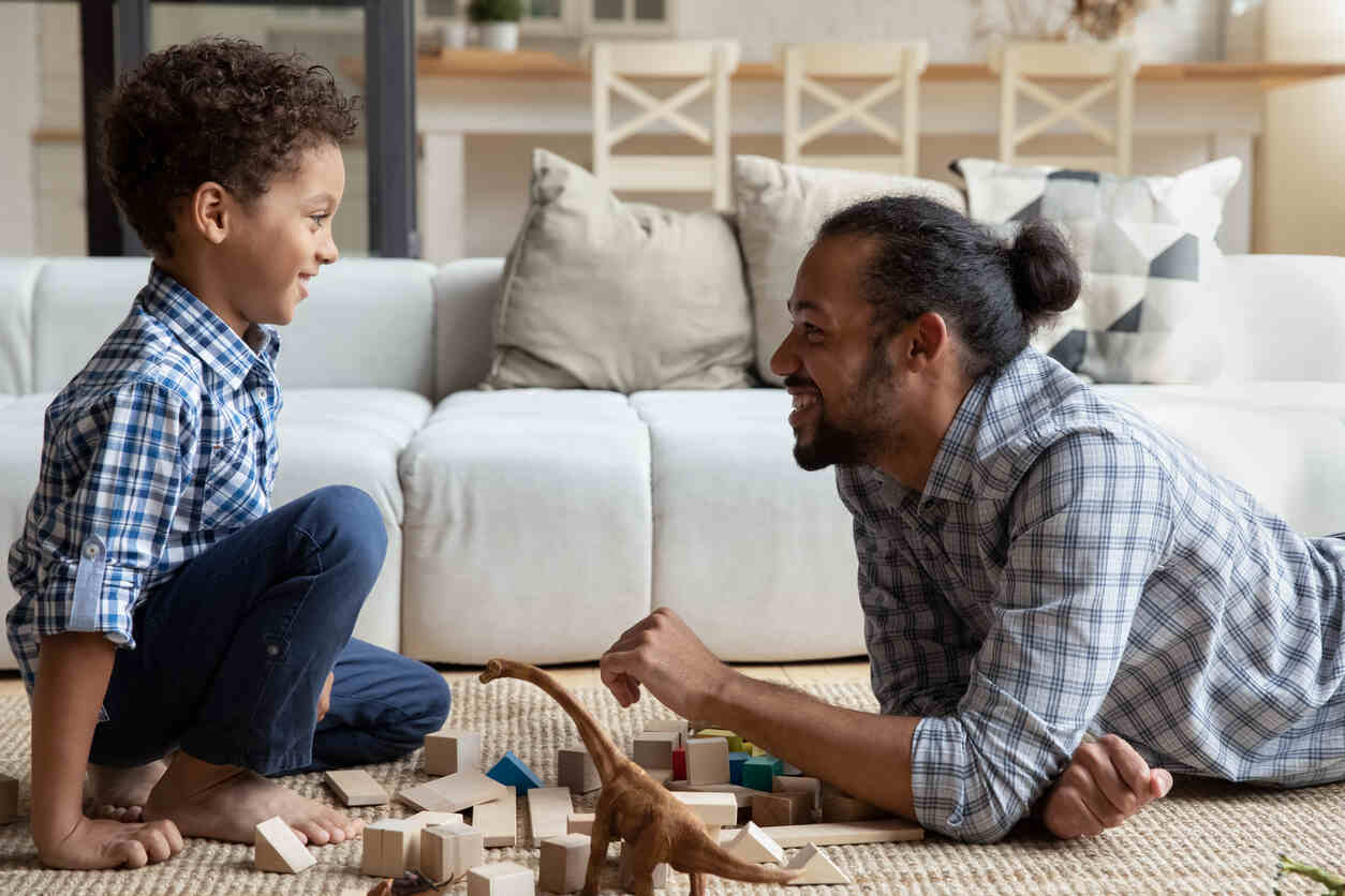 A father and young child sit on a living room floor playing with wooden blocks, reflecting how established parenting routines and the status quo can influence custody outcomes in Los Angeles.