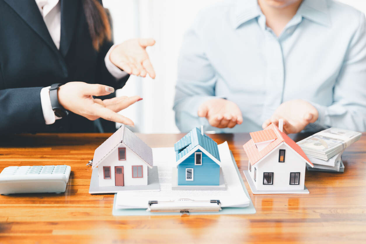 Divorce professionals reviewing property division with model houses, paperwork, and cash, representing how business ownership complicates asset division in Los Angeles divorce cases.